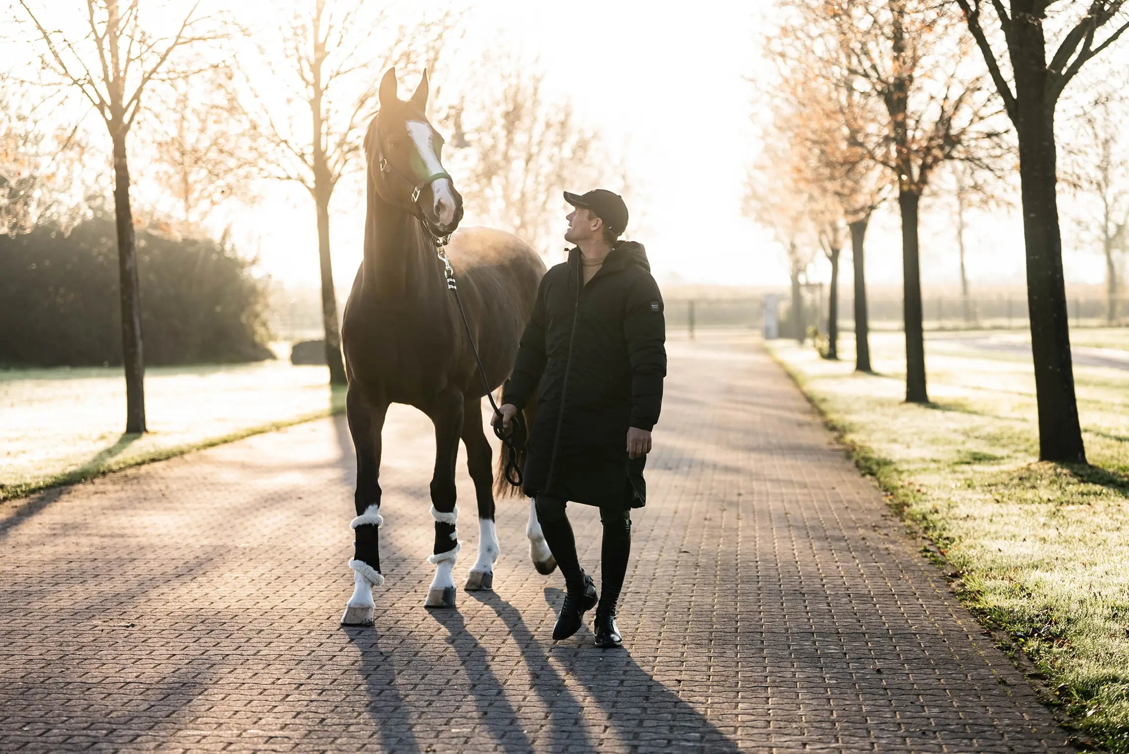 Alexander Schill walking a horse on a path with trees in the background