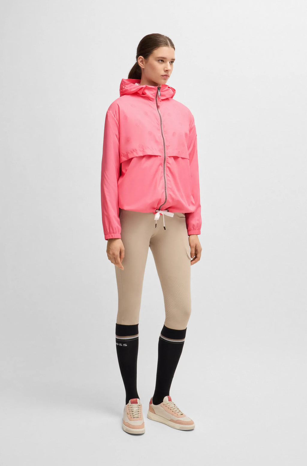 Pink | Person wearing a pink jacket, beige pants, and black knee-high socks on a white background
