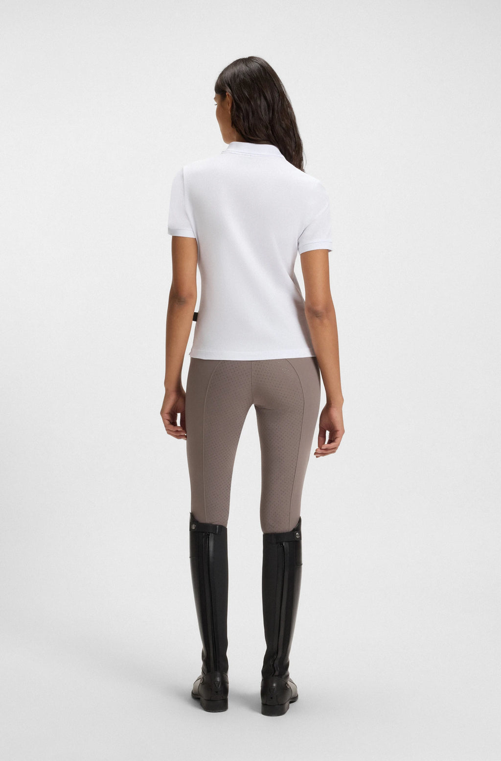 White | Person wearing a white shirt, beige leggings, and black riding boots on a white background